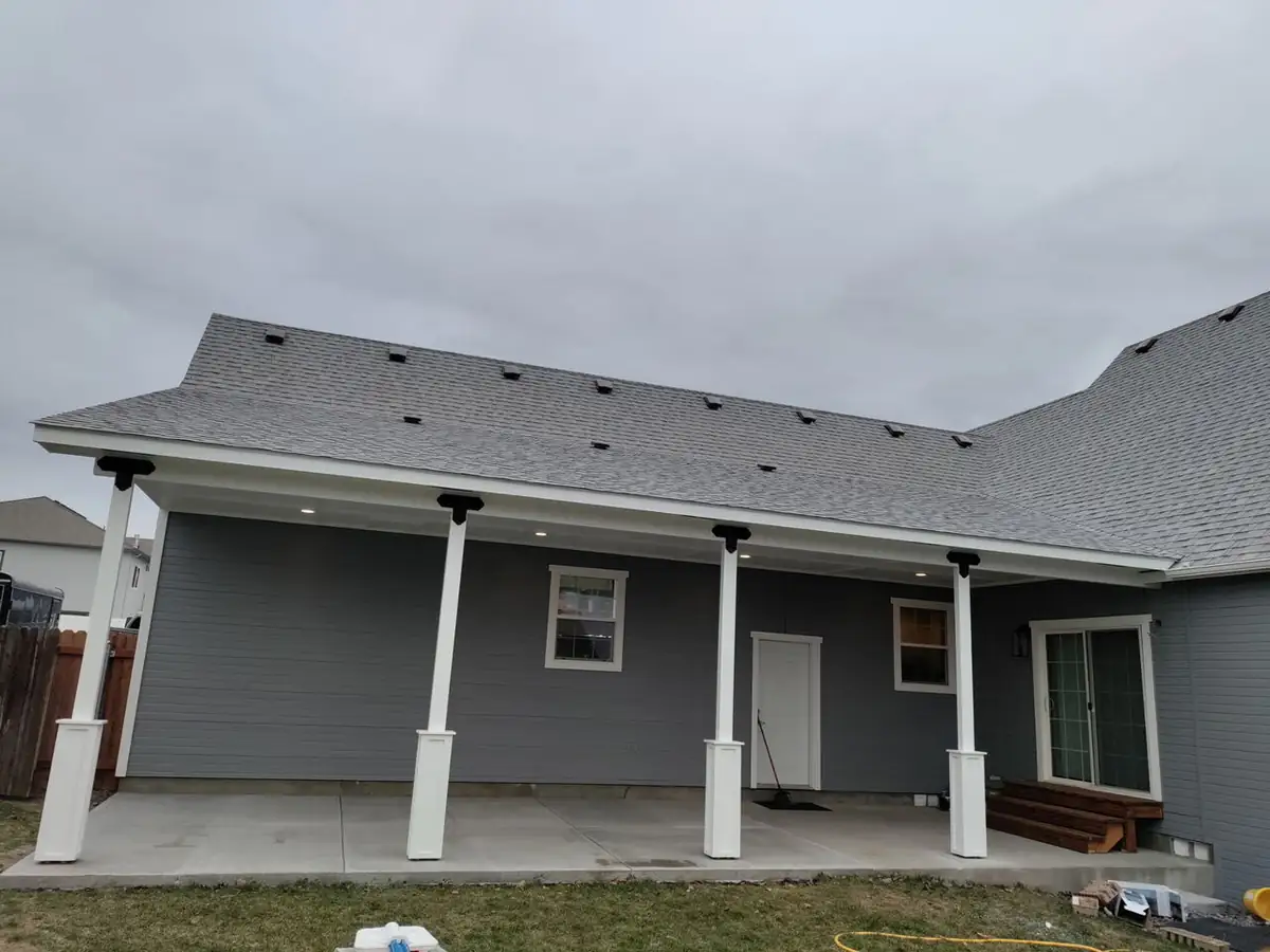 After: finished covered patio with gray siding and white columns