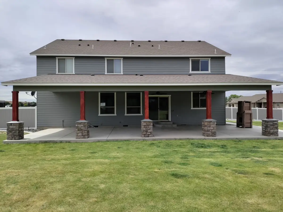After: large covered patio with red posts on stone bases
