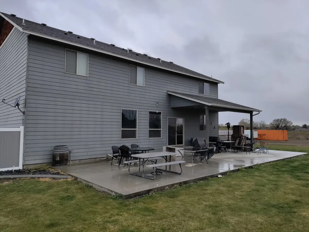 Before: bare concrete patio behind two-story home